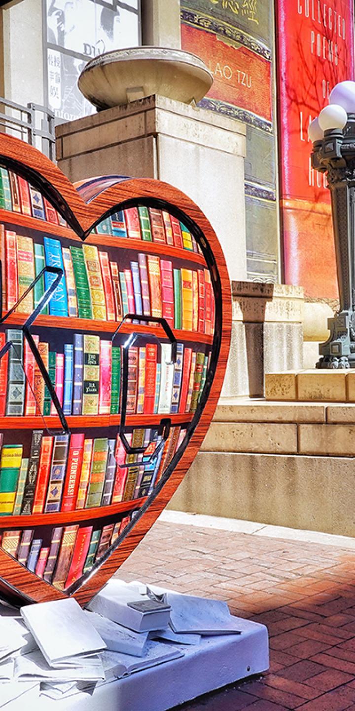 Large heart sculpture with "KC" embossed and painted to look like library shelves full of books.