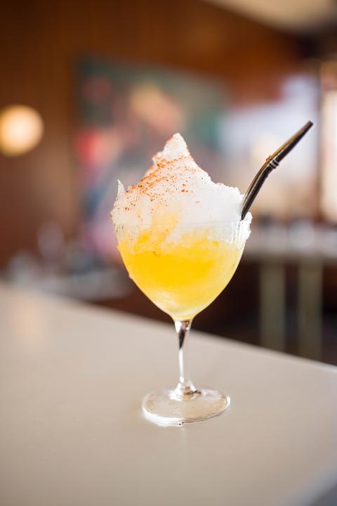 A yellow cocktail topped with freshly shaved ice.