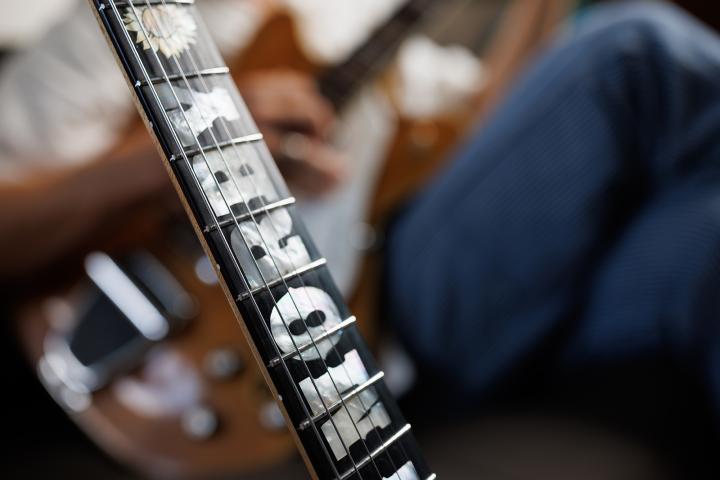 Neck of a guitar with fret inlays reading Morby