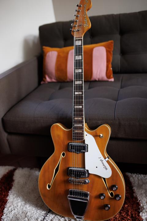 Fender guitar sitting up against a dark gray couch