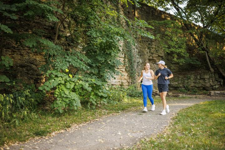 Two women jogging through a park