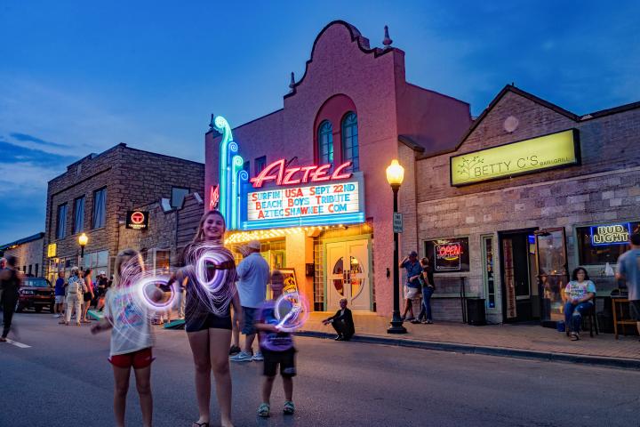 Children playing with glowsticks at an outdoor festival in front of the Aztec Theatre in Shawnee, KS