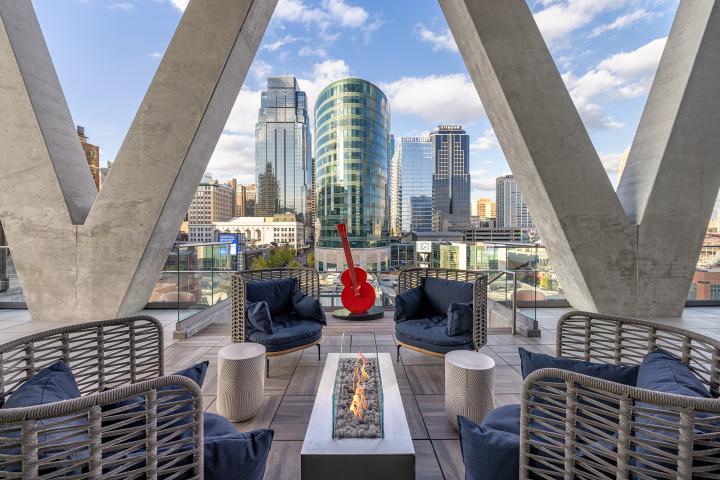 View of downtown KC from a downtown apartment lounge area, featuring chairs, a firepit and a guitar sculpture
