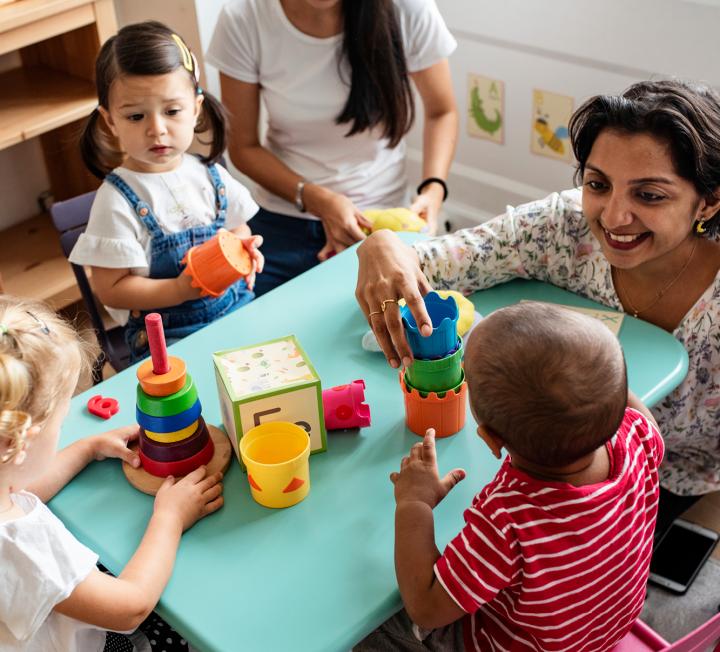 Woman playing with toddlers around a table