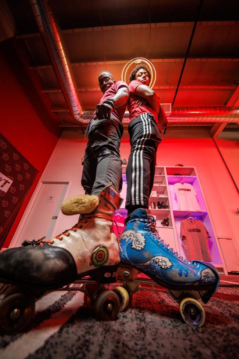 Sk8 SHOT Studios co-owners posing in their studio wearing custom roller skates