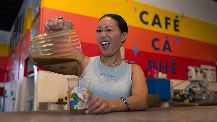 Jackie Nguyen, owner of Café Cà Phê, pouring a drink from behind the counter