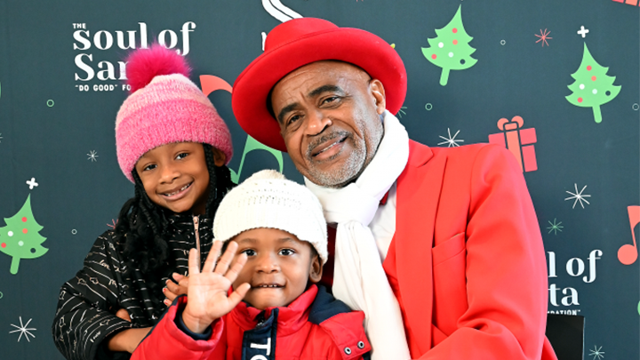 tucker lott dressed as the soul of santa, standing with two children