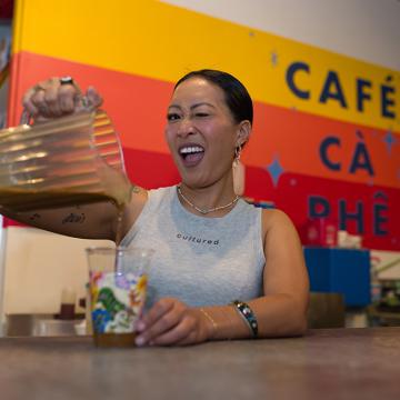 Jackie Nguyen, owner of Café Cà Phê, pouring a drink from behind the counter