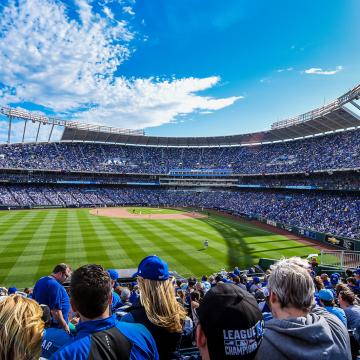 KC Royals baseball team playing at Kauffman stadium on a sunny day, with the stands full of fans
