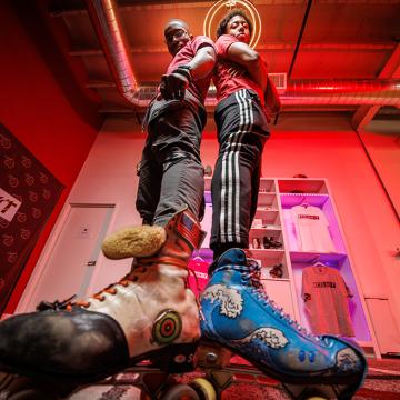 Sk8 SHOT Studios co-owners posing in their studio wearing custom roller skates